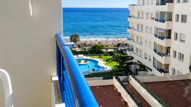 Un balcón con vista a la playa y una piscina.