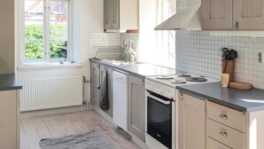 A kitchen with a window, white tiles, a stove, and cabinets. - Nice apartment in Simrishamn with WiFi (Simrishamn)