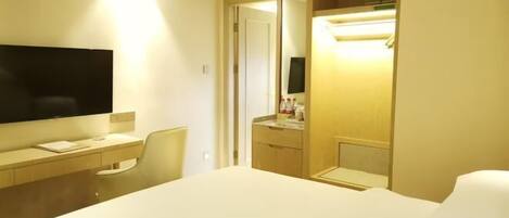 Habitación de hotel con cama, escritorio, televisor de pantalla plana, silla, armario y espejo.