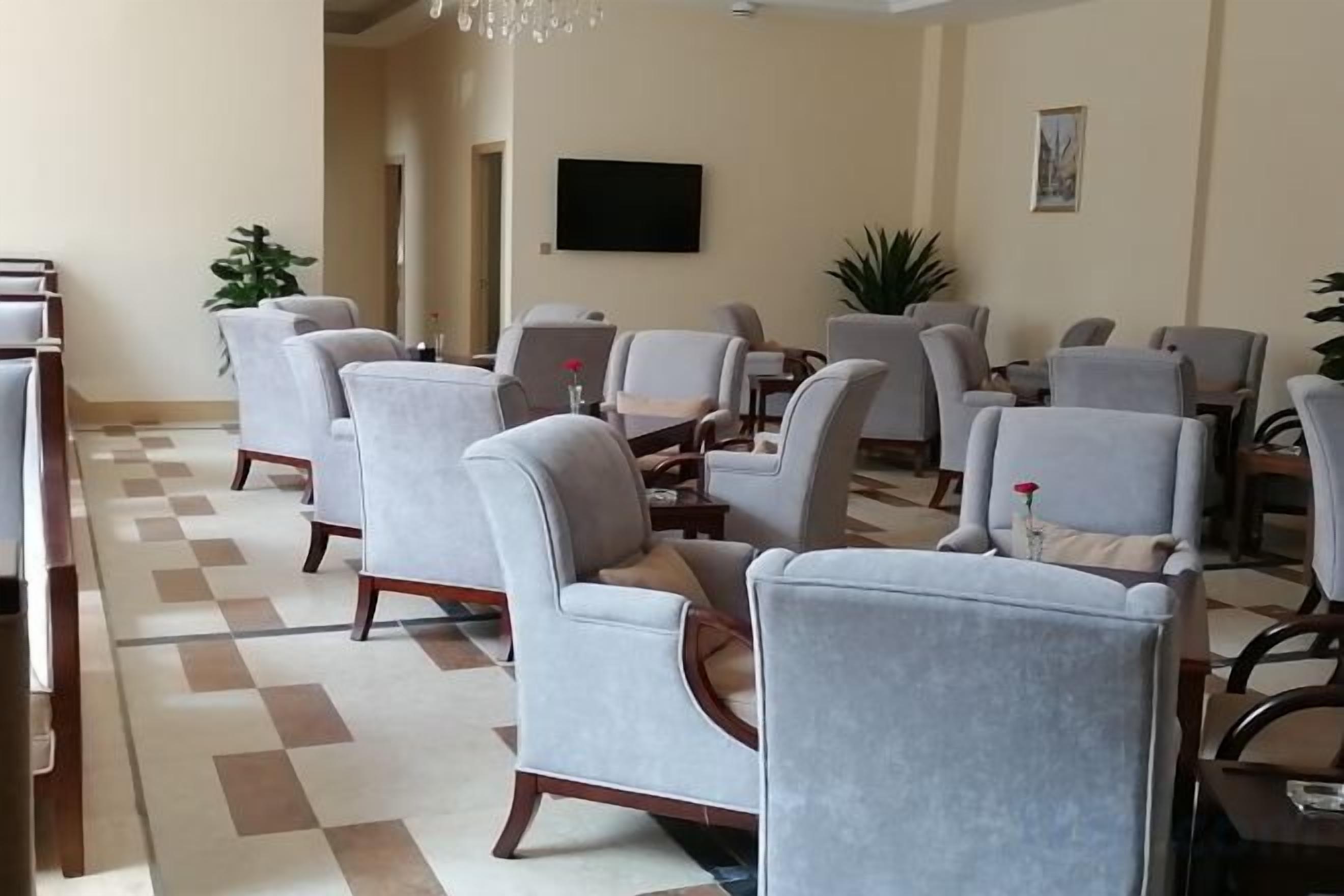 Rebedor d'hotel amb diverses zones d'estar, un televisor de pantalla plana penjat a la paret i un disseny de sòl a quadradets.
