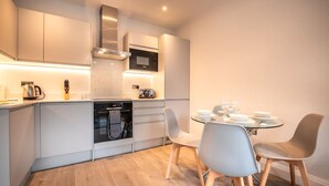 A modern kitchen with built-in appliances, a dining area with a round table and chairs, and a compact layout.