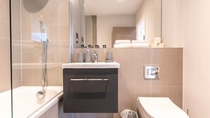 A modern bathroom with a glass-enclosed shower, a vanity with a sink, and a toilet.