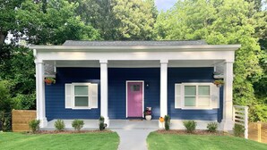 A two-story house with a dark blue exterior, white trim, and a purple door. There are two small potted plants on either side of the entrance, and a white picket fence in front. - FIFA World Cup - 4Mi to Stadium - Private Basement Apt - Free Parking - Kitchen (Atlanta)