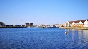 Un puerto deportivo con barcos, una boya amarilla y edificios a lo largo de la orilla.