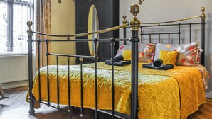 A bed with a yellow bedspread, a dark wooden wardrobe, and a window with curtains.