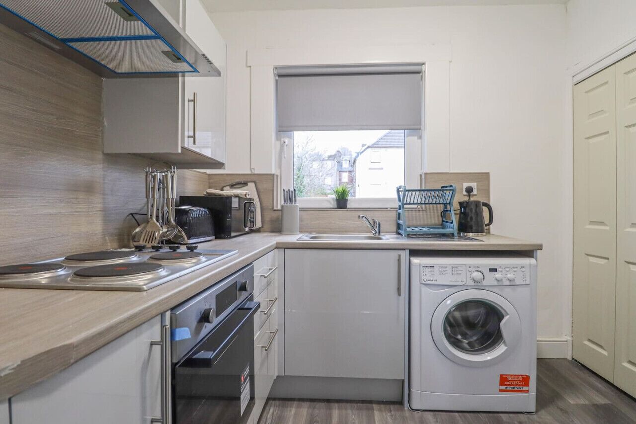 A compact kitchen with a built-in washing machine, a microwave, and a sink.