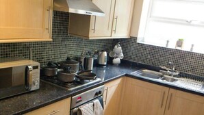 Cocina compacta con armarios de madera, microondas, estufa y un lavamanos.