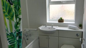 Un baño con ducha, lavamanos, inodoro y ventana.