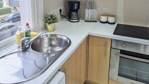 A compact kitchen with a sink, coffee maker, and stove. - 2-Bed Maida Vale flat | Little Venice, Paddington (London)