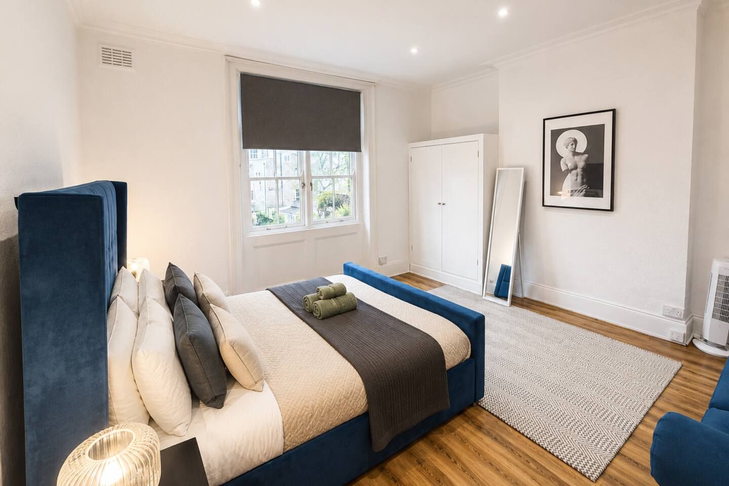 A bedroom with a bed, a wardrobe, a mirror, and a window.