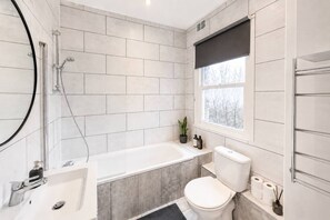 A modern bathroom with a bathtub, toilet, and sink. - 2-bed Maida Vale Flat | little venice, paddington (London)