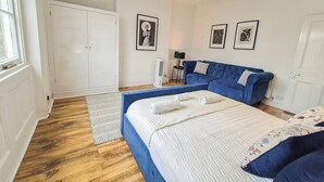 A bedroom with a large bed, a blue sofa, and a wardrobe. - 2-Bed Maida Vale flat | Little Venice, Paddington (London)