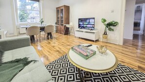 A modern living room with a dining area, a television, and a potted plant. - 2-Bed Maida Vale flat | Little Venice, Paddington (London)