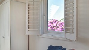 Un dormitorio con cama, ventana con contraventanas y armario.