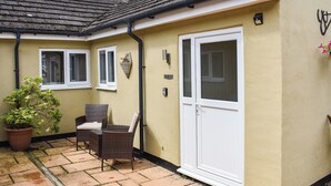 A yellow building with a tiled roof, a white door, and a window with shutters. - Roxy's Cottage - UK44687 (Beamish)