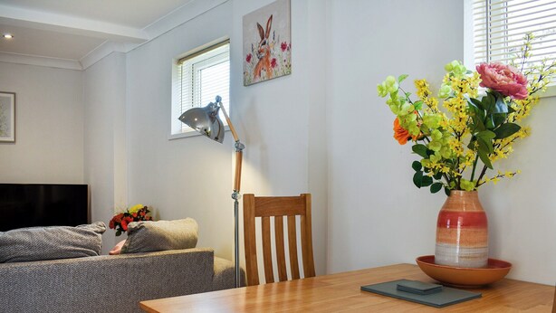 A modern living room with a wooden dining table, a sofa, a floor lamp, and a vase with flowers. - Roxy's Cottage - UK44687 (Beamish)
