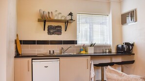 A compact kitchen with a refrigerator, a sink, and a window with blinds. - Roxy's Cottage - UK44687 (Beamish)