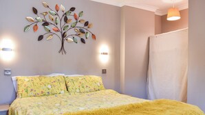 A bedroom with a bed, floral bedding, a decorative wall piece, and two wall-mounted lights. - Roxy's Cottage - UK44687 (Beamish)