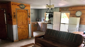 L’intérieur chaleureux d’un chalet avec un canapé en bois, une table à manger et un coin cuisine.
