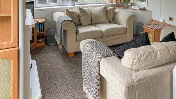 Un soggiorno accogliente con un divano color beige, una coperta decorata e una lampada su un tavolino.