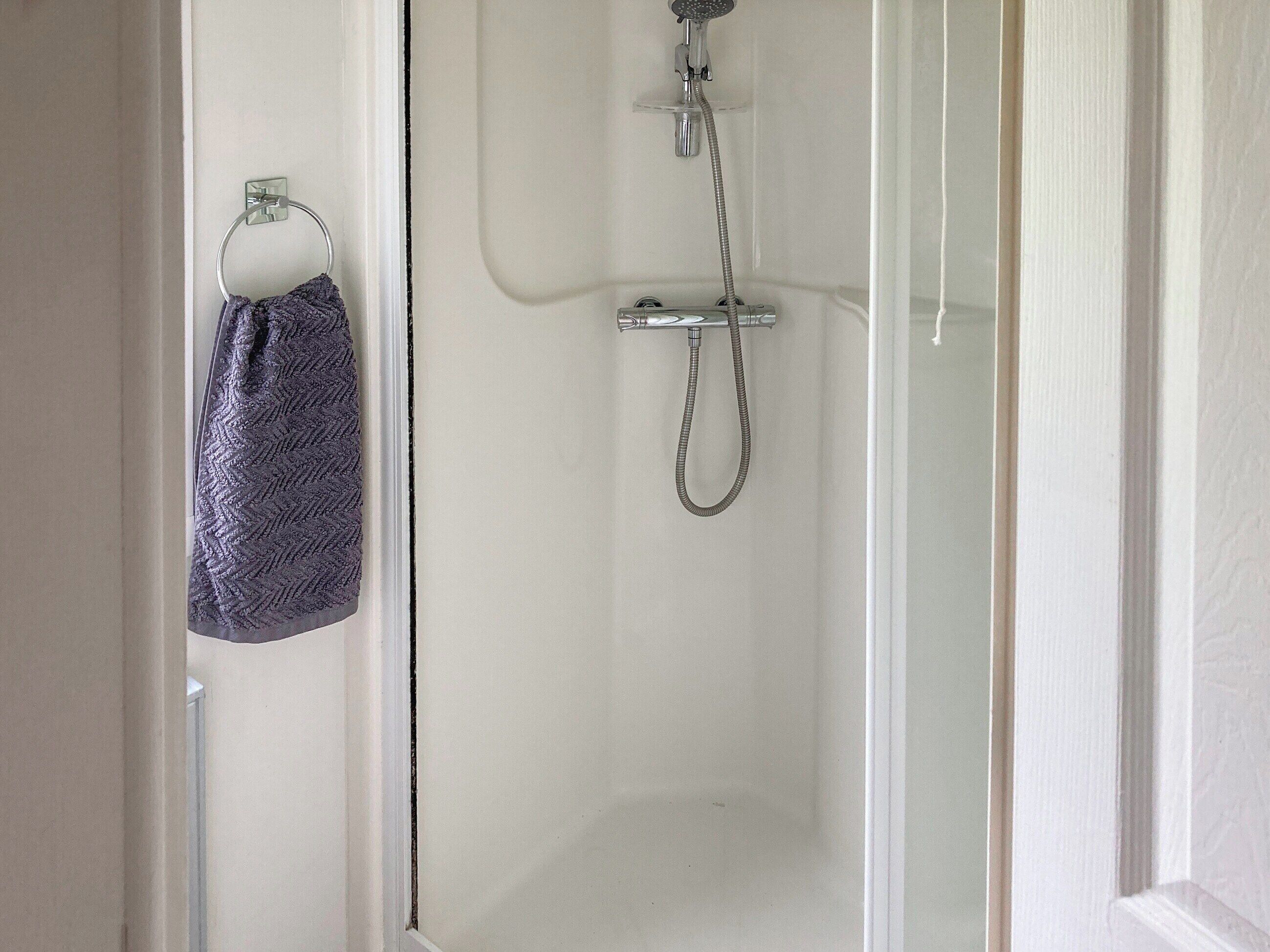 Eine Dusche mit Duschbrause und Handtuchhalter mit Handtuch.