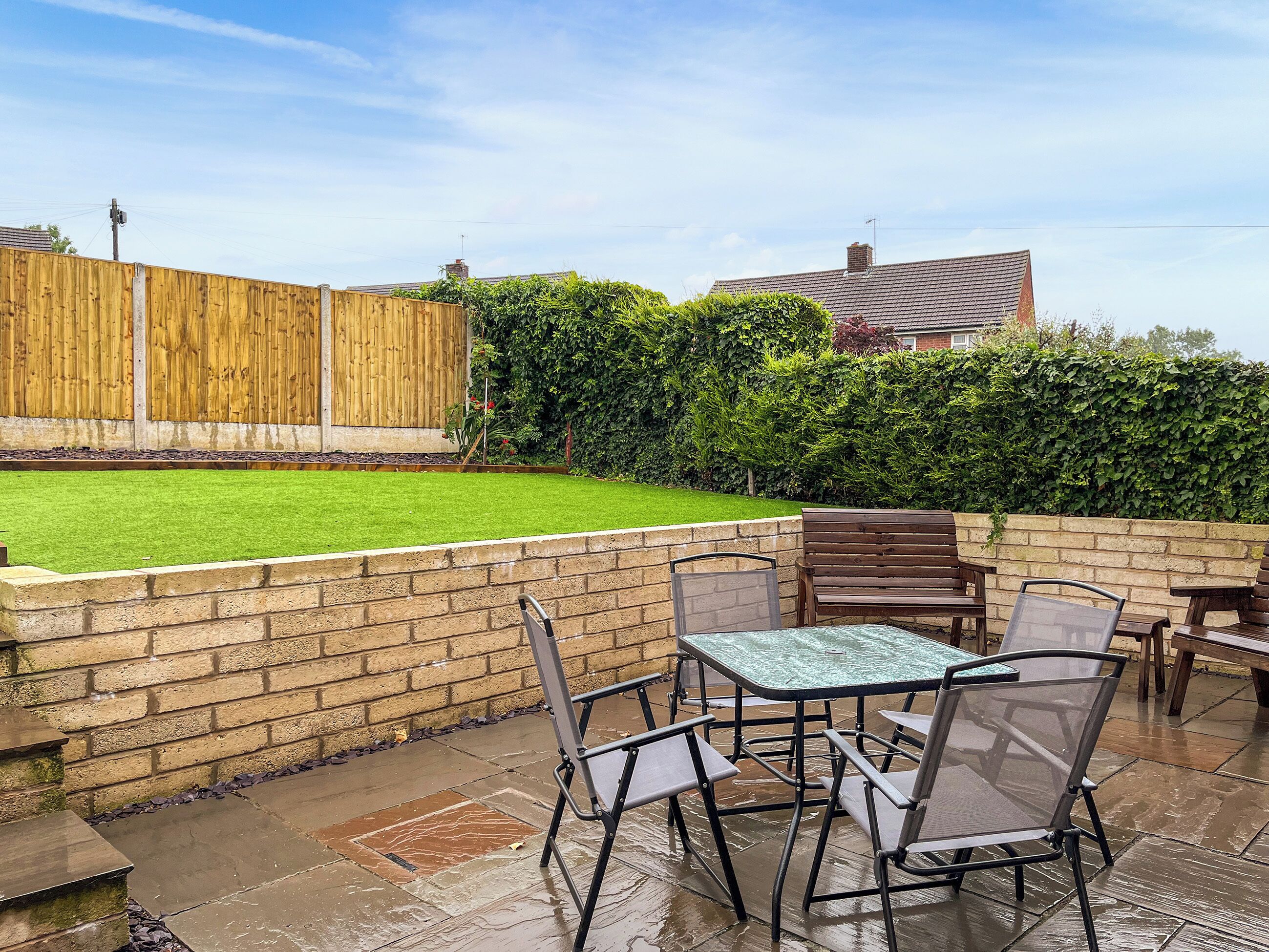 A patio area with a table and chairs, a brick wall, and a wooden fence.