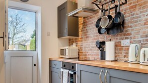 Une cuisine avec des meubles de couleur grise, un four à micro-ondes, un grille-pain et des casseroles suspendues.
