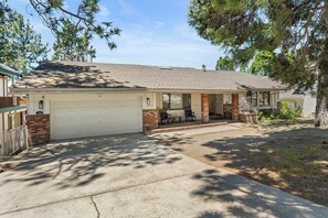 A single-story house with a garage, a covered porch with outdoor seating, and a well-maintained lawn.
