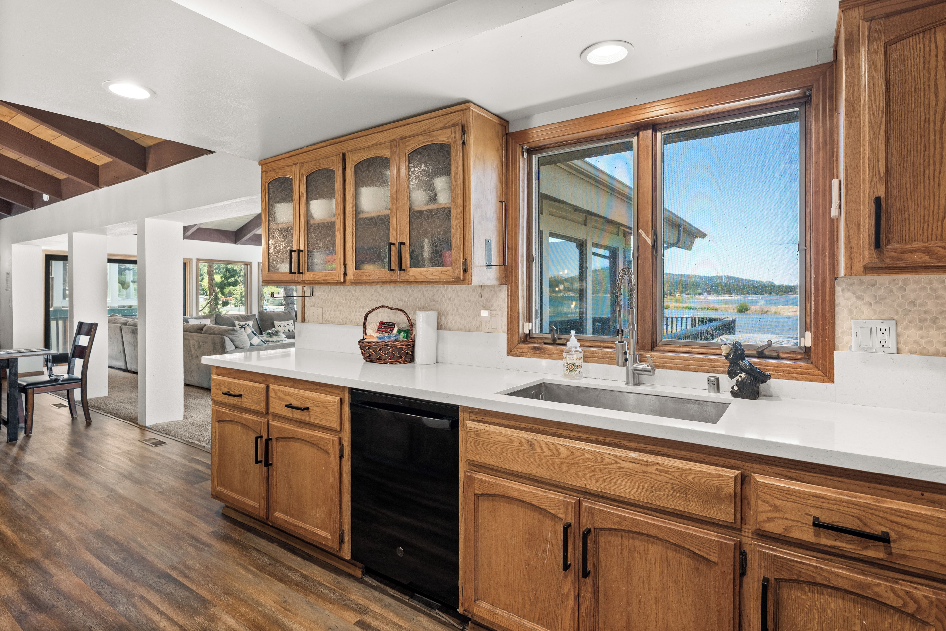 A modern kitchen with wooden cabinets, a dishwasher, and a large window offering a view of the outdoors.