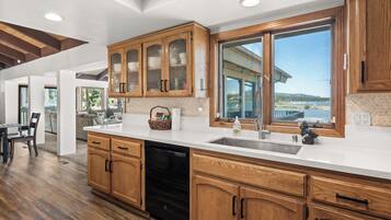 A modern kitchen with wooden cabinets, a dishwasher, and a large window offering a view of the outdoors.