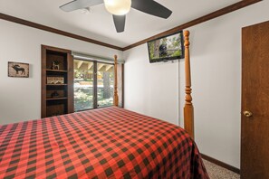A bedroom with a bed, a ceiling fan, a mounted television, and a window with a view of the outdoors. - Grand Lakefront Escape (Big Bear Lake)