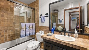 A bathroom with a bathtub, toilet, and a large mirror.