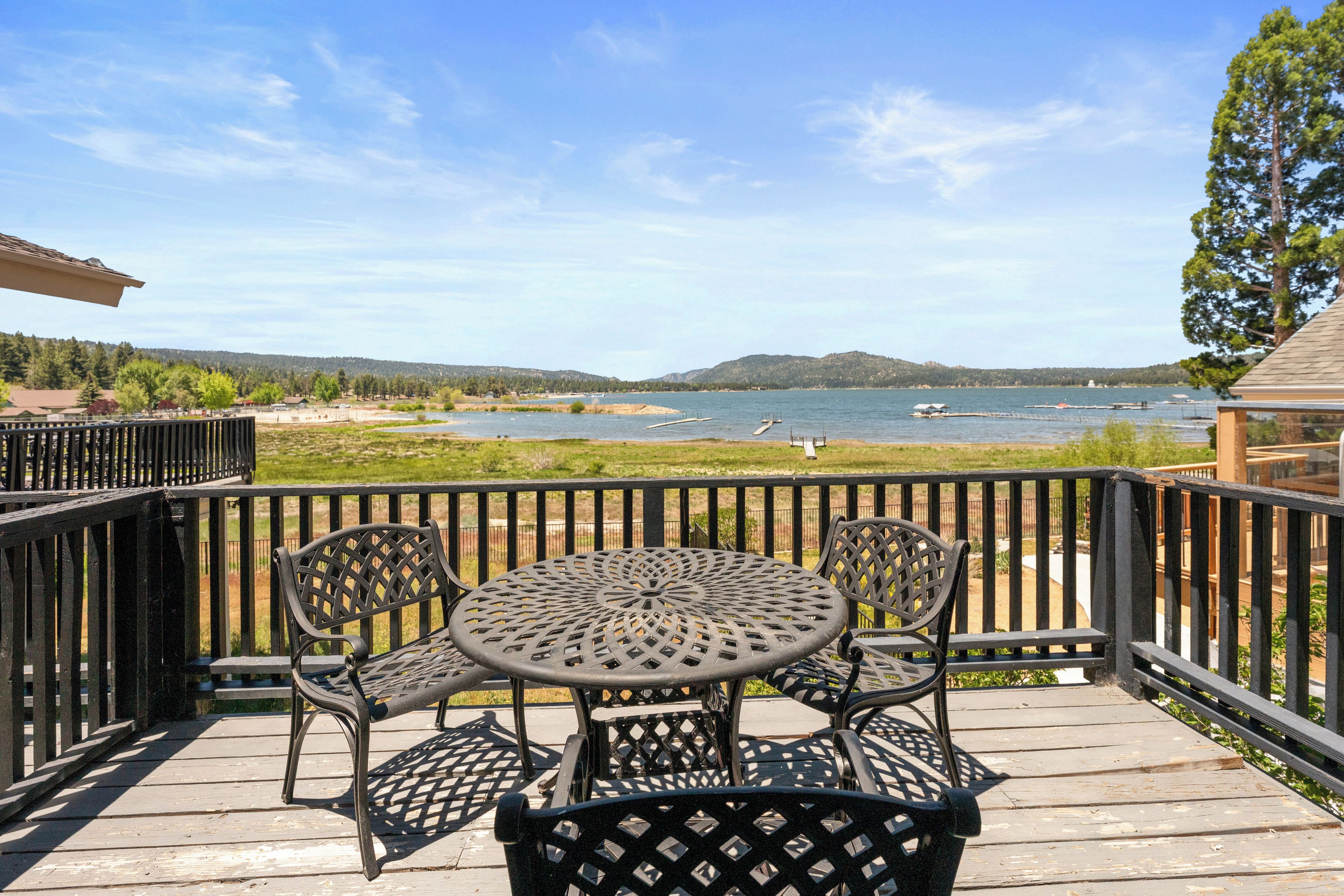 Une terrasse dotée d’une table ronde et de chaises, offrant une vue sur une étendue d’eau où se trouvent des bateaux, ainsi que sur une côte lointaine.