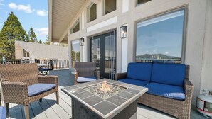 An outdoor deck with wicker furniture, a fire pit, and a view of a mountain.