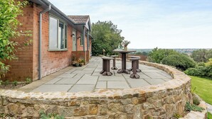 Una casa in mattoni con patio in pietra, posti a sedere all'aperto e vista sulla campagna.