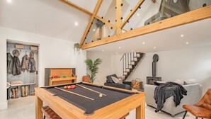 Un salon moderne avec une table de billard, un canapé, un escalier et une cheminée.