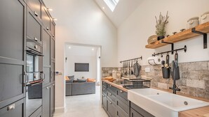 Une cuisine moderne avec des meubles de couleur sombre, un grand îlot central et un pare-feu en pierre.
