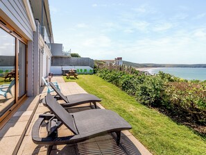 Een terras met tuinmeubilair, uitzicht op zee en een gazon.