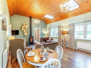A cozy living room with a fireplace, wooden ceiling, and stone wall.