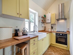 Een keuken met houten aanrecht, een spoelbak, een fornuis en kastjes.