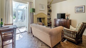 A living room with a sofa, a wooden chair, a fireplace, a television, and a bookshelf. - The Old Reading Room (Salhouse, near Norwich)