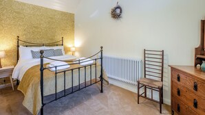 A bedroom with a bed, a radiator, a wooden chair, a dresser, and a wall with a wreath. - The Old Reading Room (Salhouse, near Norwich)