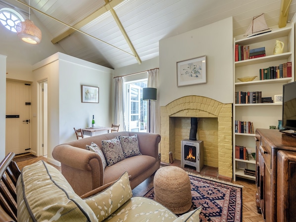 A cozy living room with a fireplace, a bookshelf, and a dining area.
