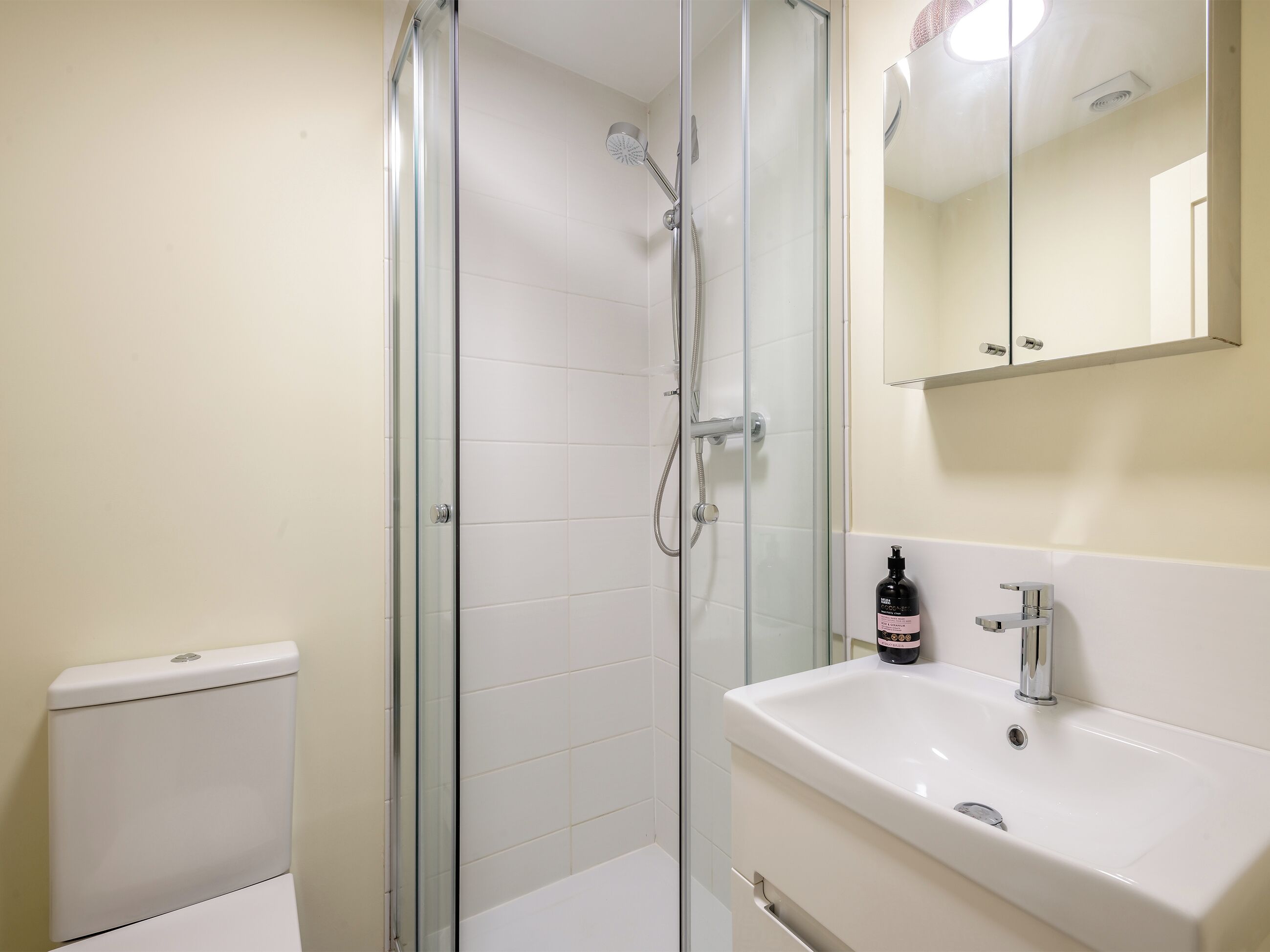 A bathroom with a glass shower enclosure, a white sink, and a toilet.