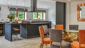 A modern kitchen with a central island, pendant lighting, and a dining area with chairs. - 5 bedroom accommodation in Diss (Diss)