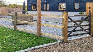 A building with a dark exterior, multiple windows, and a wooden gate. - 5 bedroom accommodation in Diss (Diss)