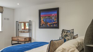 A bedroom with a bed, pillows, a bedside table, a mirror, and a framed picture on the wall. - 5 bedroom accommodation in Diss (Diss)