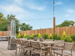 A patio with a table and chairs, a tall metal structure, and a wooden fence. - 5 bedroom accommodation in Diss (Diss)