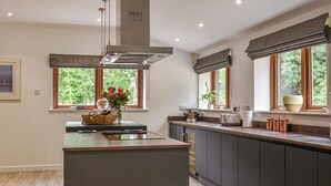 A modern kitchen with a central island, wooden countertops, and a large window with a view of greenery. - 5 bedroom accommodation in Diss (Diss)