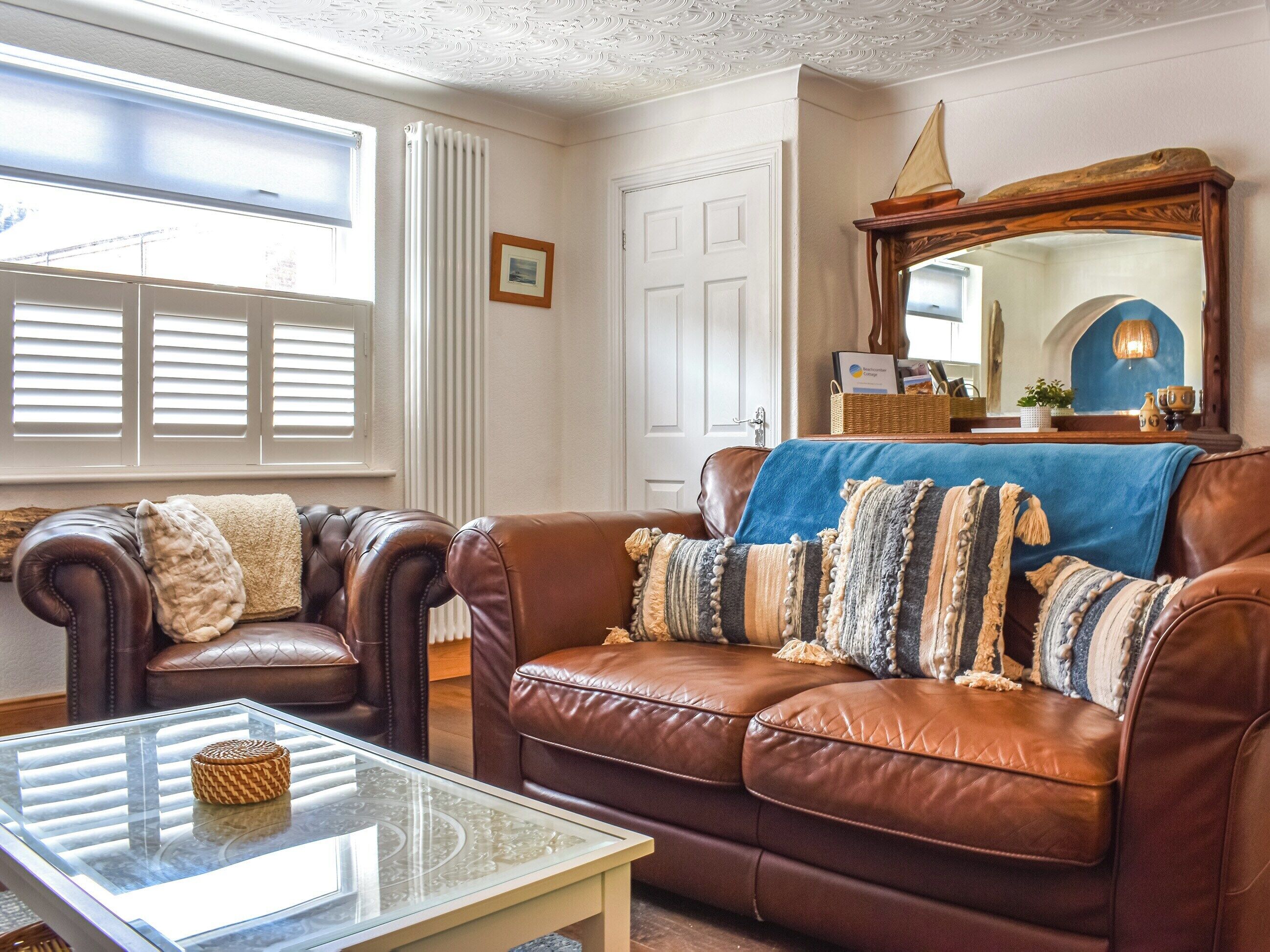 A living room with leather sofas, a glass coffee table, and a large mirror.